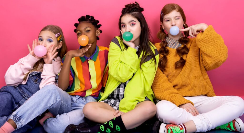 teen girls blowing gum bubbles on pink background