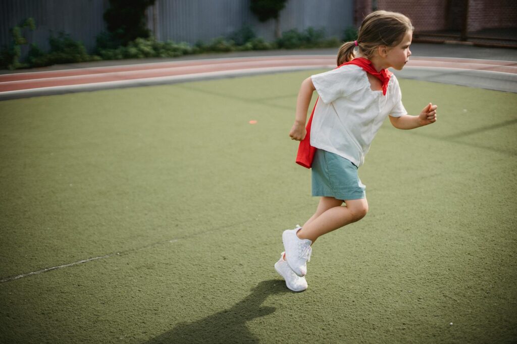little girl wearing a superhero cape running